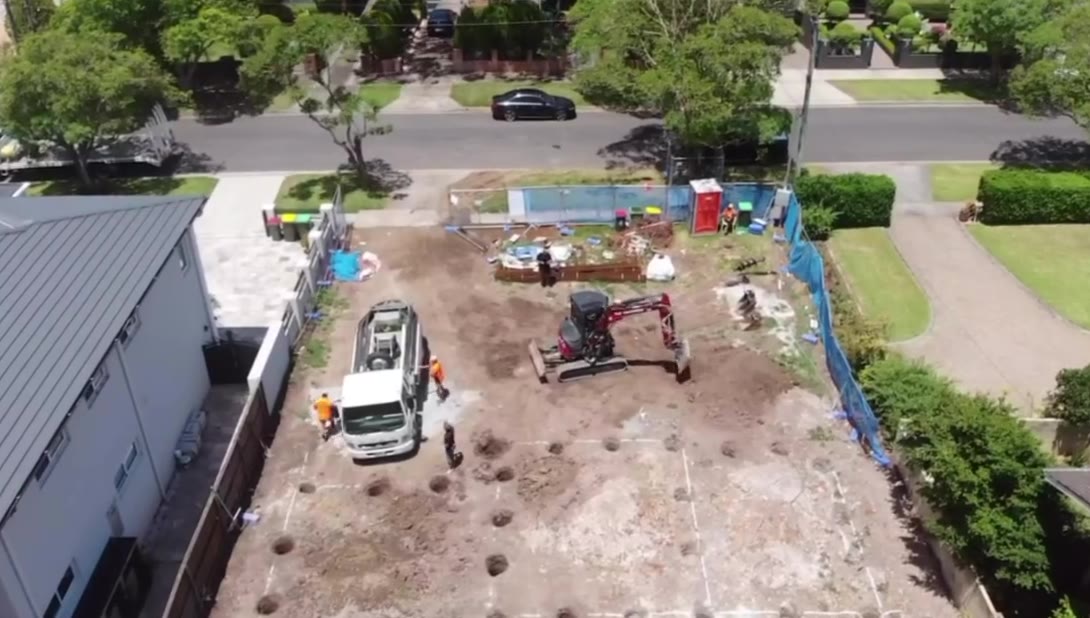 Truck and excavator on a cleared residential block, drone view