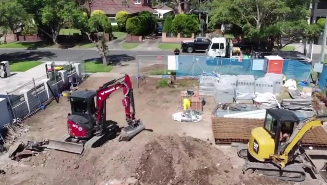 Two excavators working a residential site, seen from a drone