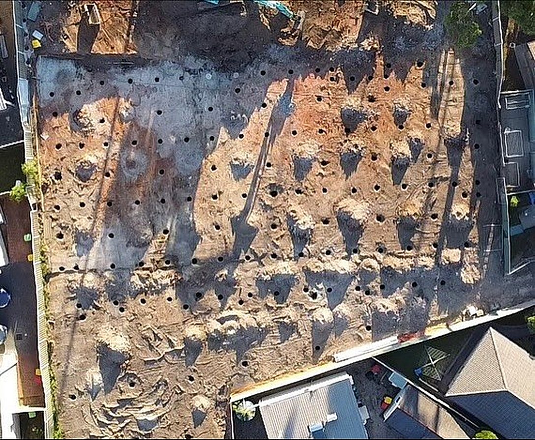 Rows of pier holes drilled across a site, top-down drone view